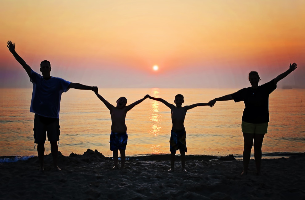 Family holding hands at the beach during sunset