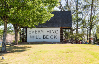 A sign saying everything will be ok on an old barn