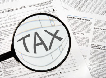 Federal tax forms under a magnifying glass.