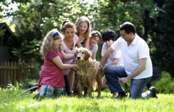 A family giving their dog a bath on the lawn