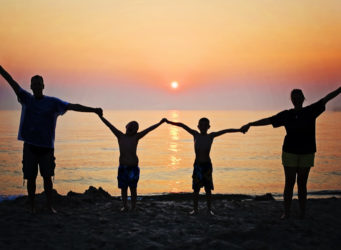 Family holding hands at the beach during sunset